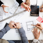 Picture of businessmen's hands on white table with documents, coffee and drafts